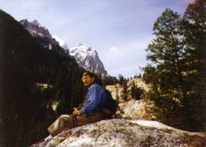 Charles Fracé sitting on a rock outcrop